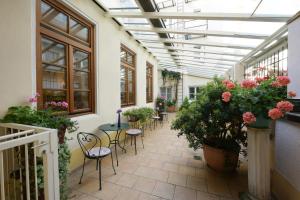 une serre avec des tables, des chaises et des plantes dans l'établissement Hotel Eder, à Munich