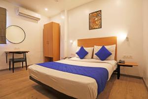 Hotel A4U sector 45 Gurgaon في جورجاون: غرفة فندق بسرير كبير مع وسائد زرقاء