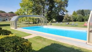 una piscina con un arco sobre ella en un patio en la ferme des ruelles, en Moigny