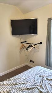 een flatscreen-tv hangend aan een muur naast een bed bij ACCOMADATION WREXHAM in Wrexham