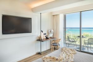 a hotel room with a tv and a bed and a balcony at Erato by Samian Mare in Karlovasi