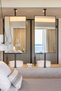 a bedroom with two mirrors and a bed with white pillows at Erato by Samian Mare in Karlovasi