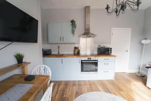 a kitchen with white cabinets and a wooden table at Oldfield Apartments - Bath in Bath