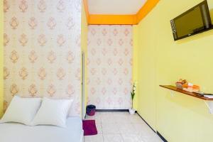 - une chambre avec un lit et une télévision murale dans l'établissement Sion Homestay Mitra RedDoorz near Terminal Kertajaya Mojokerto, 