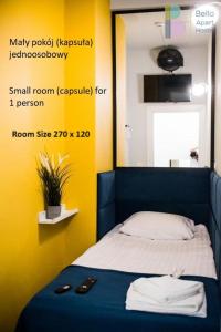 a small room with a bed with yellow walls at Bello ApartHostel in Warsaw