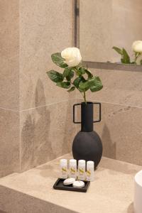 a black vase with a white rose and four slippers at Erato by Samian Mare in Karlovasi