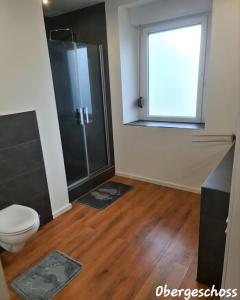 uma casa de banho com um chuveiro, um WC e uma janela. em APARTMENT MONTEURZiMMER AM BAHNSTEIG em Kuppenheim