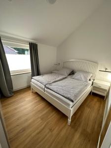 1 dormitorio con cama blanca y ventana en Ferienhaus Fam. Mersmann, en Papenburg