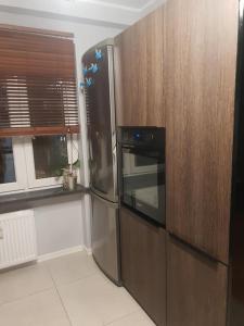 La cuisine est équipée d'un réfrigérateur en acier inoxydable et de placards en bois. dans l'établissement KWATERY PRACOWNICZE, à Środa Wielkopolska