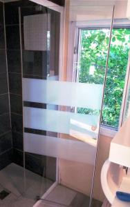 a glass shower in a bathroom with a window at Au Temps Suspendu - 3 chambres - Au coeur de la nature - À 10 minutes des commerces in Vielle-Tursan