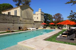 a swimming pool with chairs and umbrellas in front of a building at Château de Pondres in Villevieille