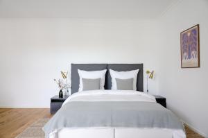 a white bedroom with a large bed with white pillows at R7 Berlin in Berlin