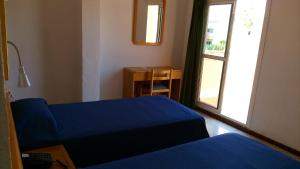 una camera con un letto blu e una finestra di Hotel Bari a Can Pastilla