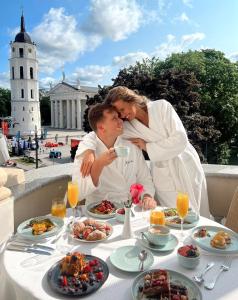 un homme et une femme assis à une table avec de la nourriture dans l'établissement Grand Hotel Vilnius, Curio Collection by Hilton, à Vilnius