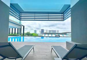 uma vista para uma piscina com duas cadeiras em Twin Tower Johor custom Ciq Nearest walk by YHA em Johor Bahru