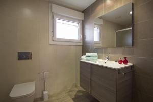 ein Badezimmer mit Waschbecken, Toilette und Spiegel in der Unterkunft Apartamento Rural La Patxuela in Obanos