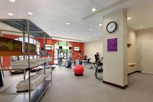 a gym with a clock on a wall and machines at Home2 Suites by Hilton Tuscaloosa Downtown University Boulevard in Tuscaloosa