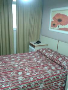 Habitación de hotel con cama con manta roja y blanca en Hotel Venezuela, en Río de Janeiro