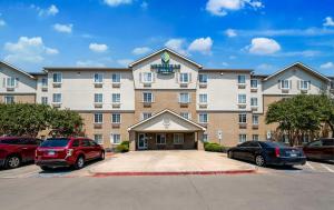 un hotel con coches estacionados en un estacionamiento en WoodSpring Suites Fort Worth Fossil Creek en Fort Worth
