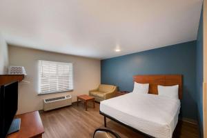 um quarto com uma cama, uma secretária e uma cadeira em WoodSpring Suites Fort Worth Fossil Creek em Fort Worth