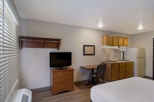 a small room with a bed and a desk with a television at WoodSpring Suites Jacksonville I-295 East in Jacksonville