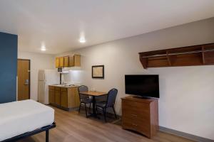 Habitación pequeña con cama y mesa pequeña con TV. en WoodSpring Suites Jacksonville I-295 East, en Jacksonville