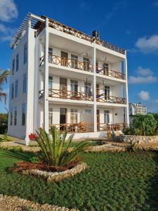 Un gran edificio blanco con un patio delante. en Five Seasons Zanzibar opposite Mnemba island Hotel, en Makunge