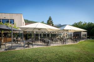 un patio avec des tables et des chaises sous des parasols dans l'établissement Domaine de Charmeil, à Saint-Quentin-sur-Isère