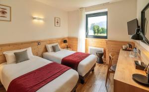 a hotel room with two beds and a desk and a window at Domaine de Charmeil in Saint-Quentin-sur-Isère