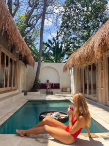 a woman sitting in front of a swimming pool at Amahelia Luxury Resort & Restaurant - Gili Asahan in Gili Asahan