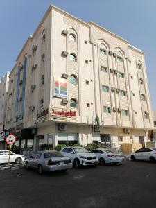 un grande edificio con macchine parcheggiate di fronte di المواسم الأربعة للوحدات السكنية a Tabuk