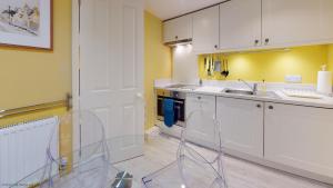 a kitchen with white cabinets and a clear chair in it at The Jericho Studio in Oxford