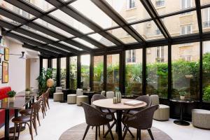 巴黎Hôtel Moderniste的有桌椅和大窗户的餐厅