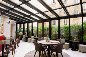 un restaurante con mesas, sillas y ventanas grandes en Hôtel Moderniste, en París