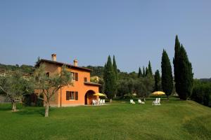 una casa naranja con sillas y sombrillas en un patio en Poiano Garda Resort Appartamenti, en Garda