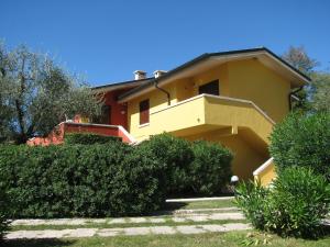 une maison jaune avec des buissons devant elle dans l'établissement Poiano Garda Resort Appartamenti, à Garde