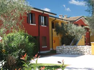 une maison rouge et jaune avec un mur en pierre dans l'établissement Poiano Garda Resort Appartamenti, à Garde