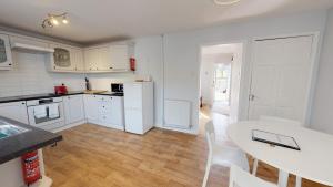 a kitchen with white cabinets and a white table and chairs at Taphouse Avenue in Crawley