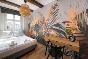 sypialnia z łóżkiem, biurkiem i malowidłem ściennym w obiekcie AtHome Toruń Apartamenty w Toruniu