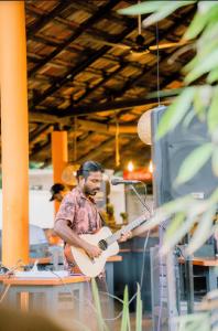 un homme jouant de la guitare devant un microphone dans l'établissement Daffodil Restaurant & Holiday Resort, à Unawatuna
