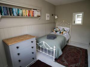 a bedroom with a bed and a dresser with books at Beautiful Country Cottage in Hayfield