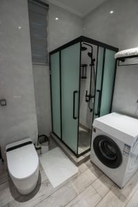 a bathroom with a toilet and a shower and a washing machine at Waterlily Guesthouse in Beau Vallon