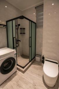 a bathroom with a shower and a toilet and a washing machine at Waterlily Guesthouse in Beau Vallon