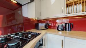 a kitchen with a stove and a red wall at Market Place Cottage in Woodstock