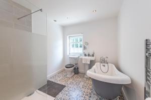 a bathroom with a tub and a toilet and a sink at Bay Cottage in Malpas