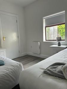 a white bedroom with a bed and a window at Eyre Square Lane Budget Rooms in Galway