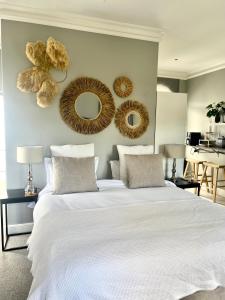 1 dormitorio con 1 cama blanca y 2 espejos en la pared en Esme Road - WE HAVE NO LOADSHEDDING!, en Ciudad del Cabo