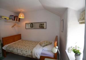 a small bedroom with a bed and a mirror at The White Cottage in Woodstock