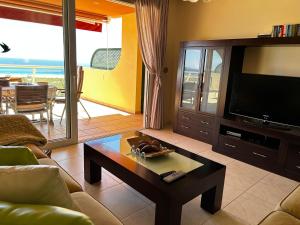 - un salon avec un canapé, une télévision et une table dans l'établissement Terrazas de Jandía, à Morro del Jable