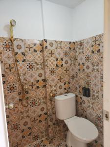 a bathroom with a toilet and a tiled wall at Kamar Apartemen Harian by Younz Apartmen Depok in Pondokcina